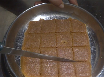 cutting the bella kayi burfi or coconut jaggery burfi mixture