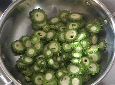 frying bittergourd slices for hagalakayi or bitter gourd fry