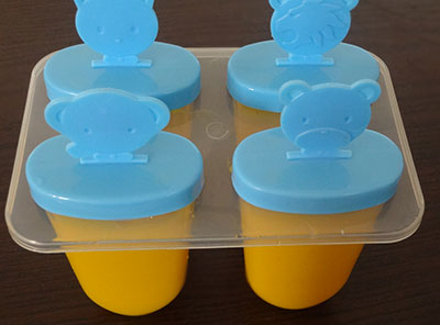 pour mango puree into popsicle moulds for mango popsicles