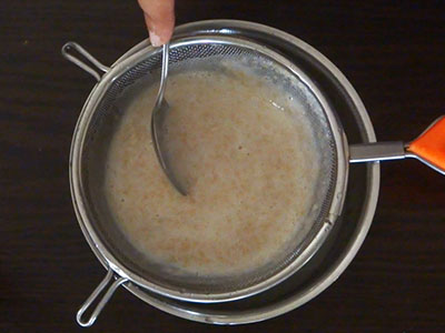 straining the ground paste for southe beejada saru or cucumber seeds rasam